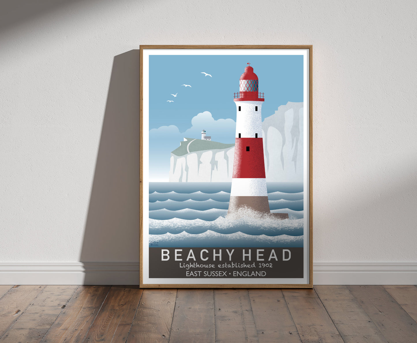 Framed illustration of a red and white striped lighthouse, rugged white cliffs, and a rough sea 