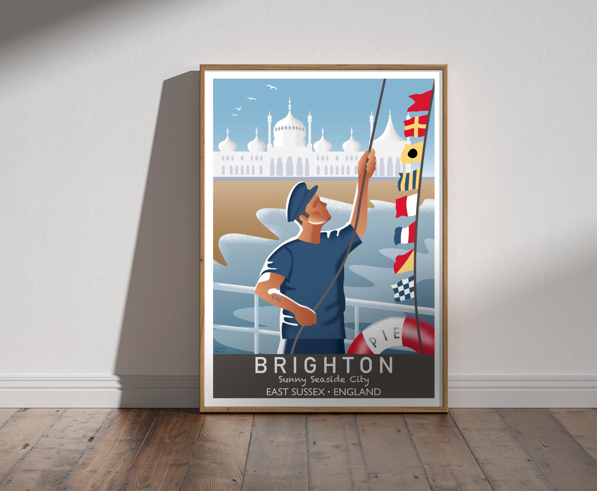 Framed illustration of a sailor raising nautical flags on Brighton pier, with a white Saracenic onion-domed building in background 