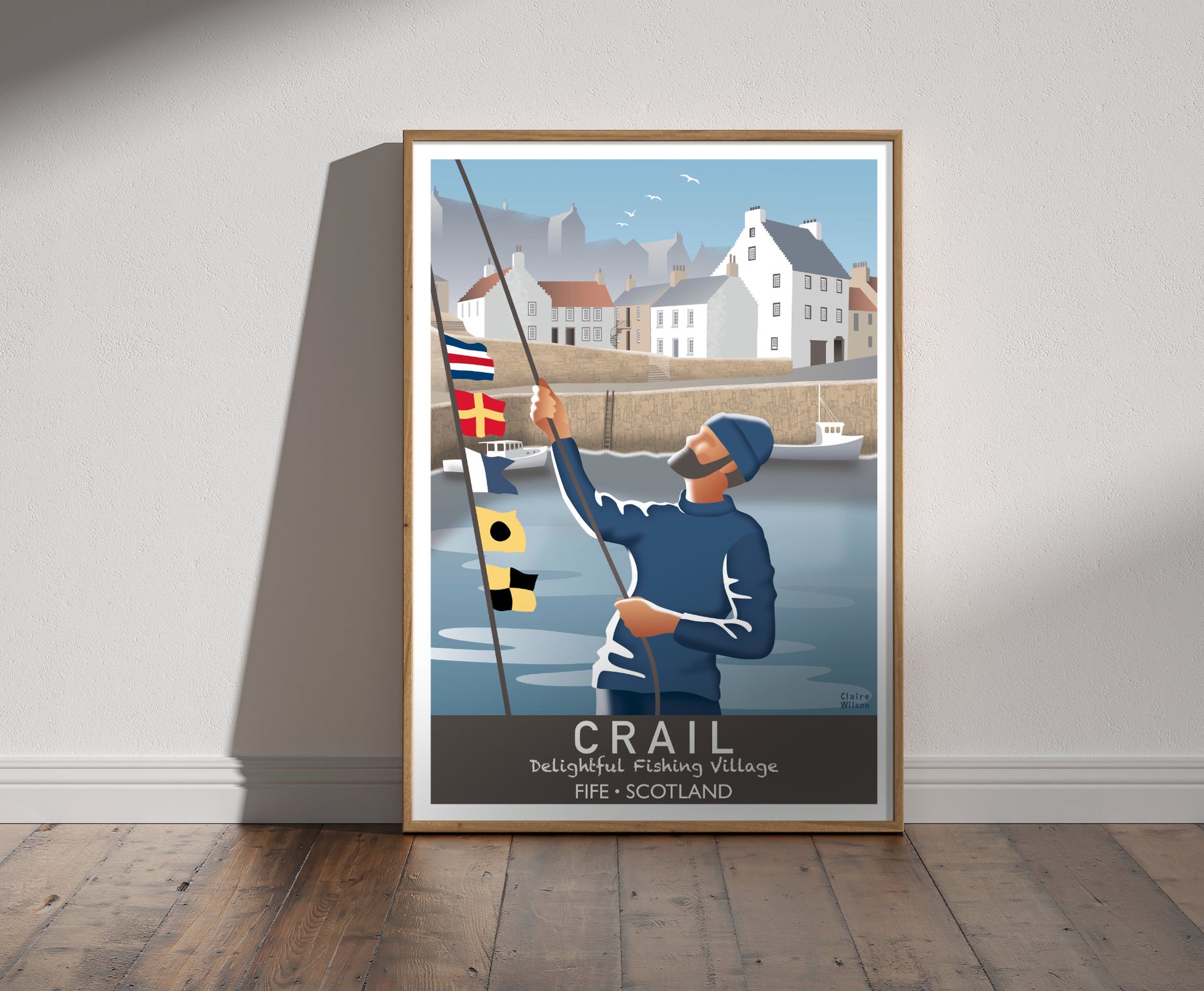 Framed illustration of a sailor raising nautical flags at Crail harbour, with historic white houses with crow stepped gables in the background 