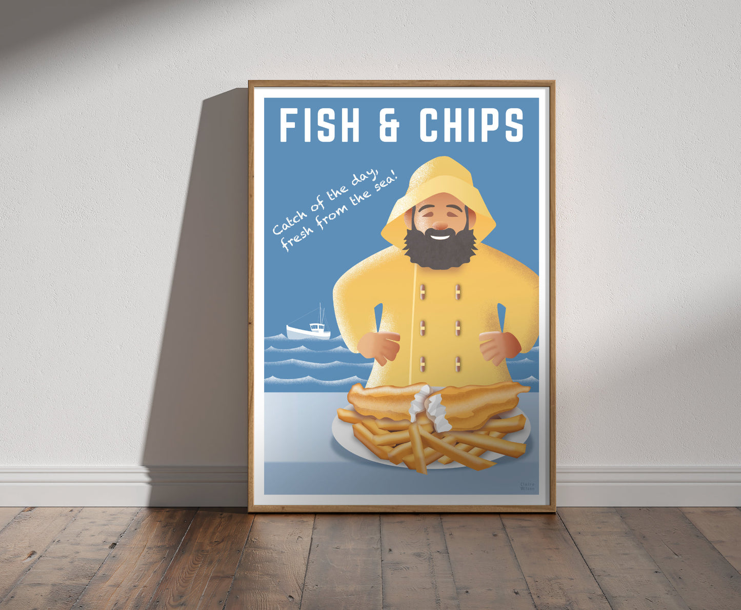 Framed illustration of a happy fisherman in yellow jacket with a plate of fish and chips, and a boat and sea in background 