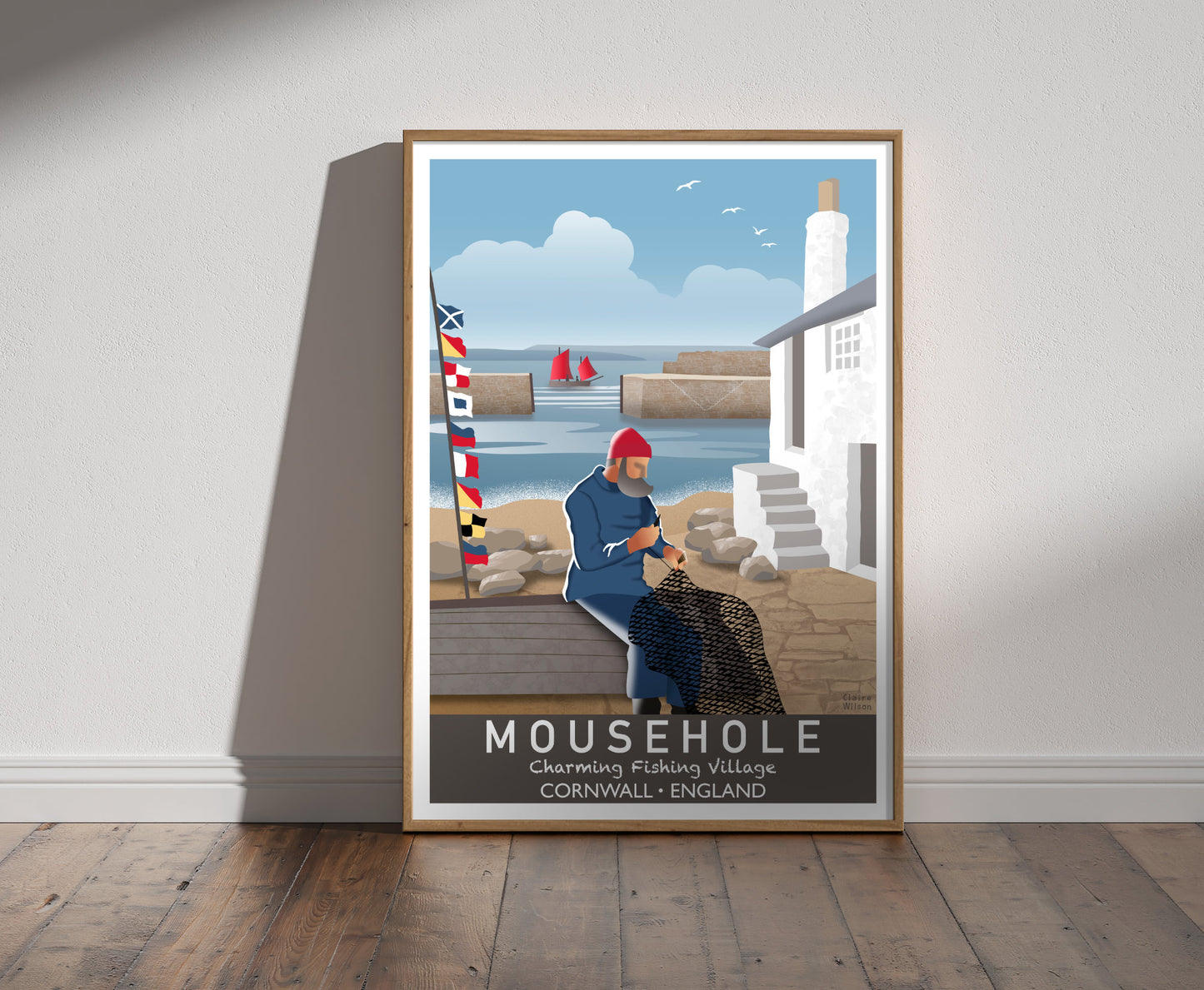 Framed illustration of a fisherman mending his nets by a white cottage at Mousehole, with nautical flags, harbour and fishing boat in background  