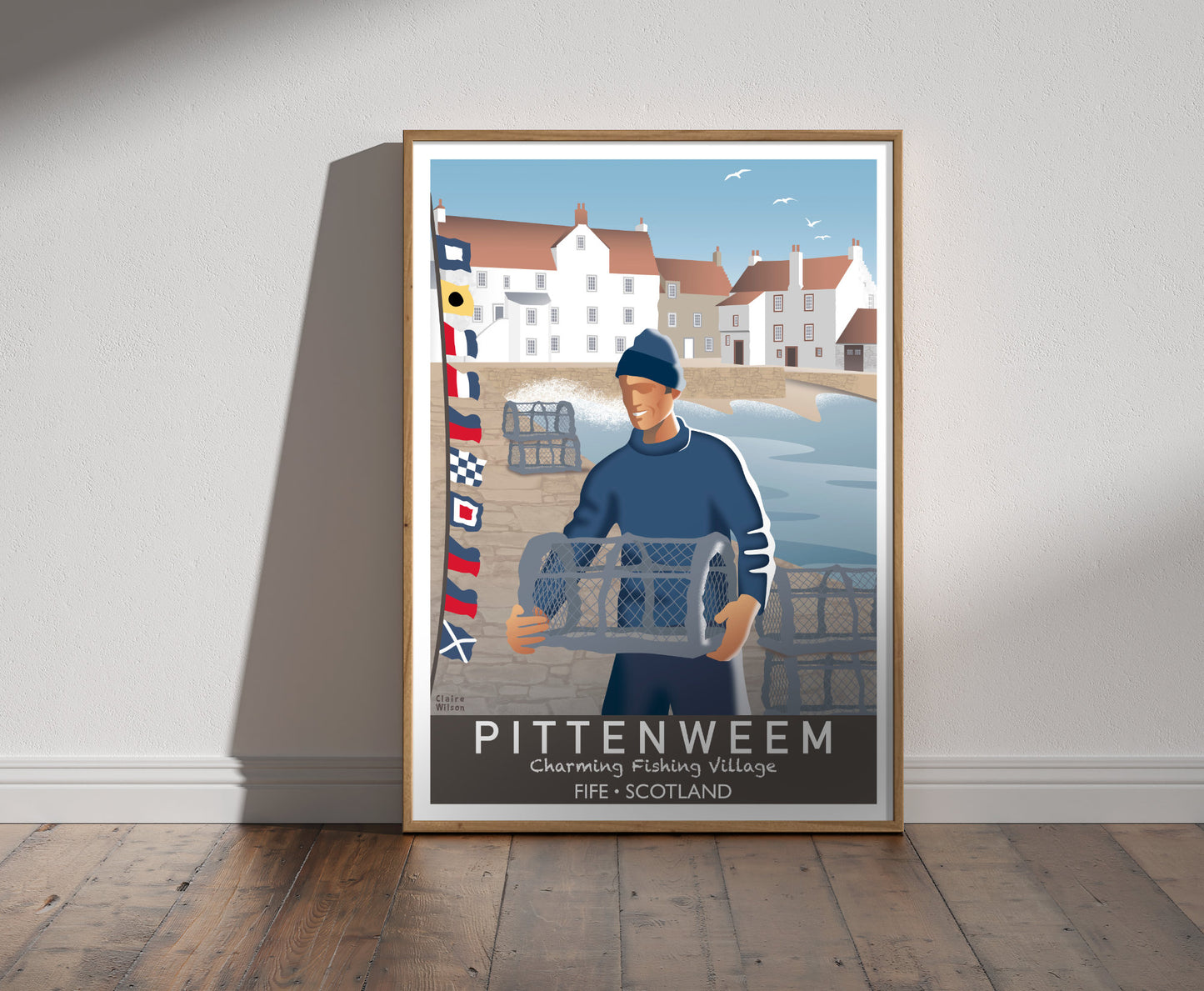 Framed illustration of a sailor carrying lobster trap and nautical flags at Pittenweem harbour, and historic white houses with crow stepped gables in the background 