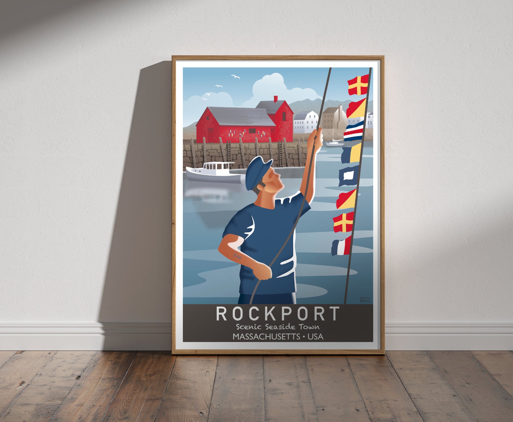 Framed illustration of a sailor raising nautical flags in Rockport harbour, with a red fishing shack and boats in background 