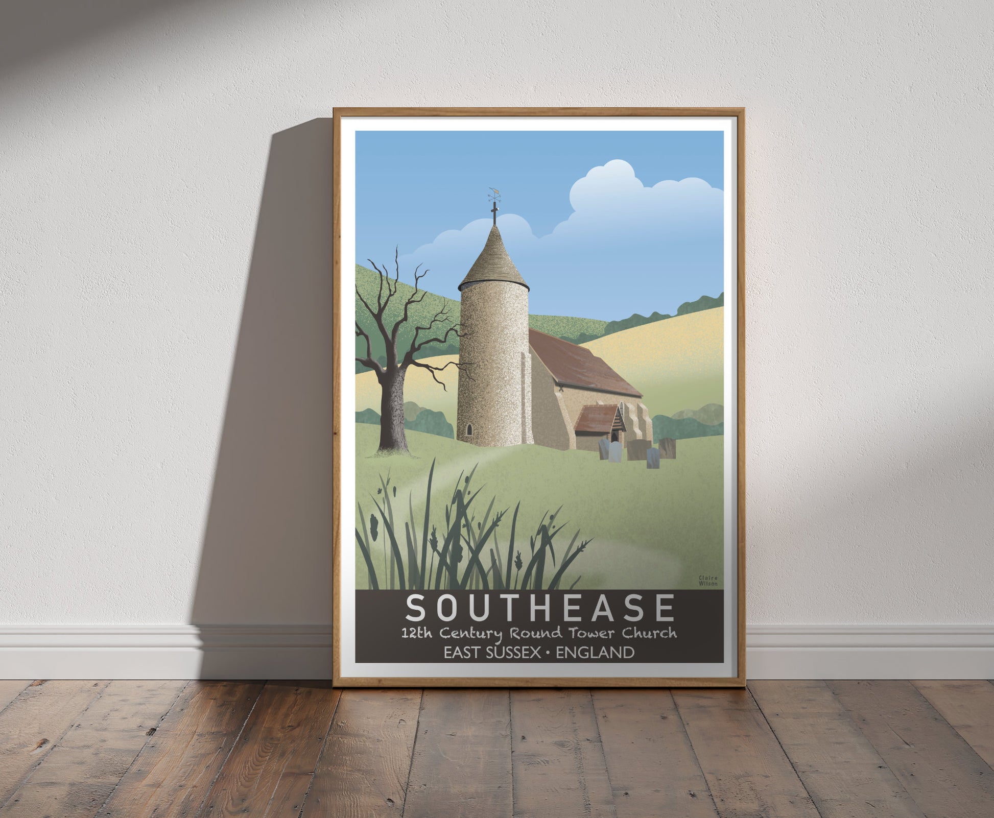 Framed illustration of a church with a round tower, a gnarled tree and countryside hills in the background