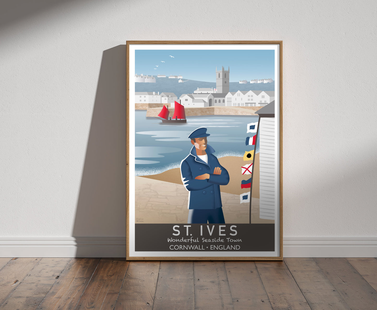 Framed illustration of a sailor and nautical flags at St Ives harbour, with old church, seaside buildings and a boat in background 